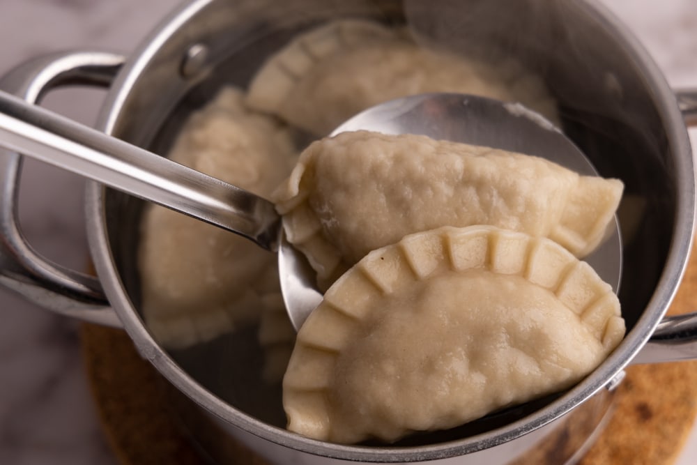 Removing cooked pierogi using a slotted spoon