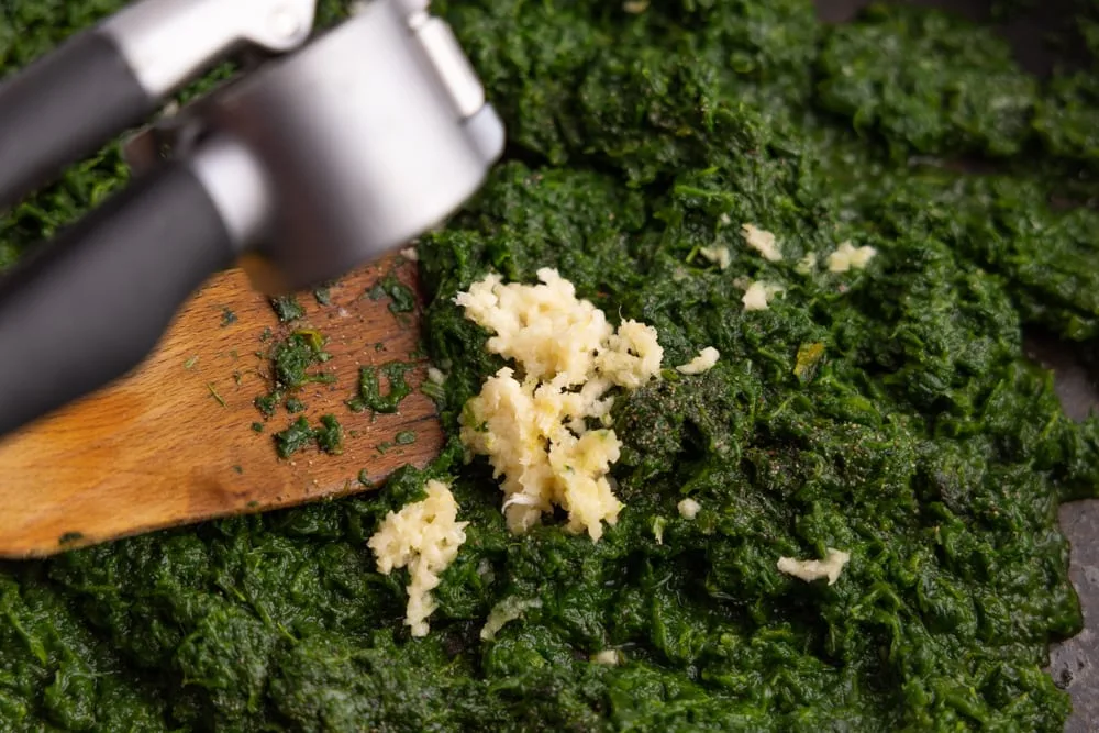 Adding pressed garlic to cooked spinach