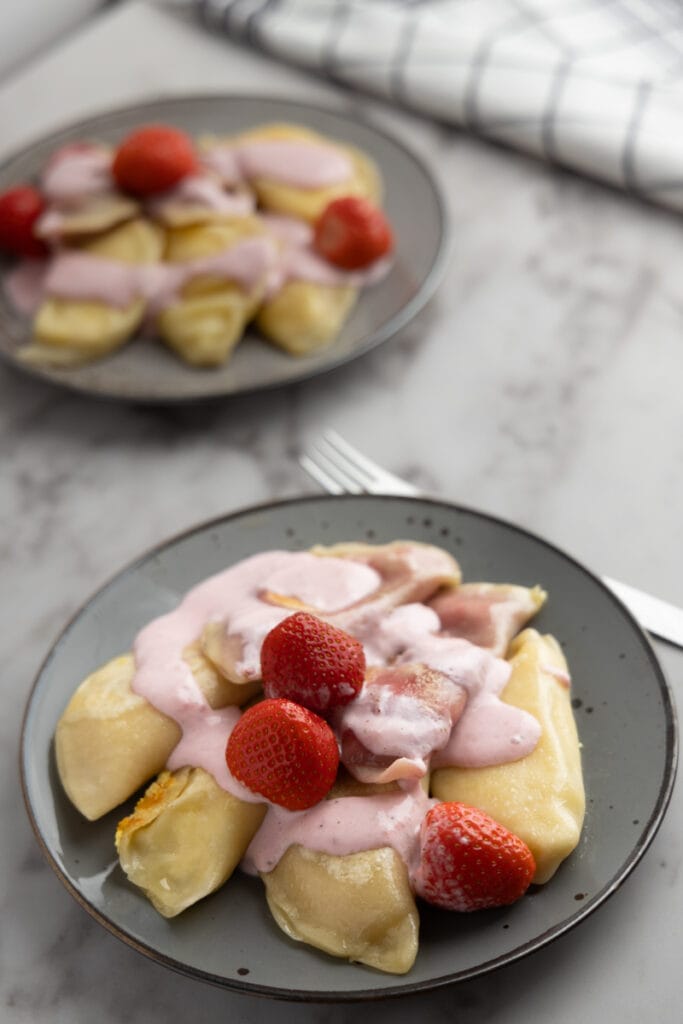 Two servings of farmers cheese pierogi with strawberry topping