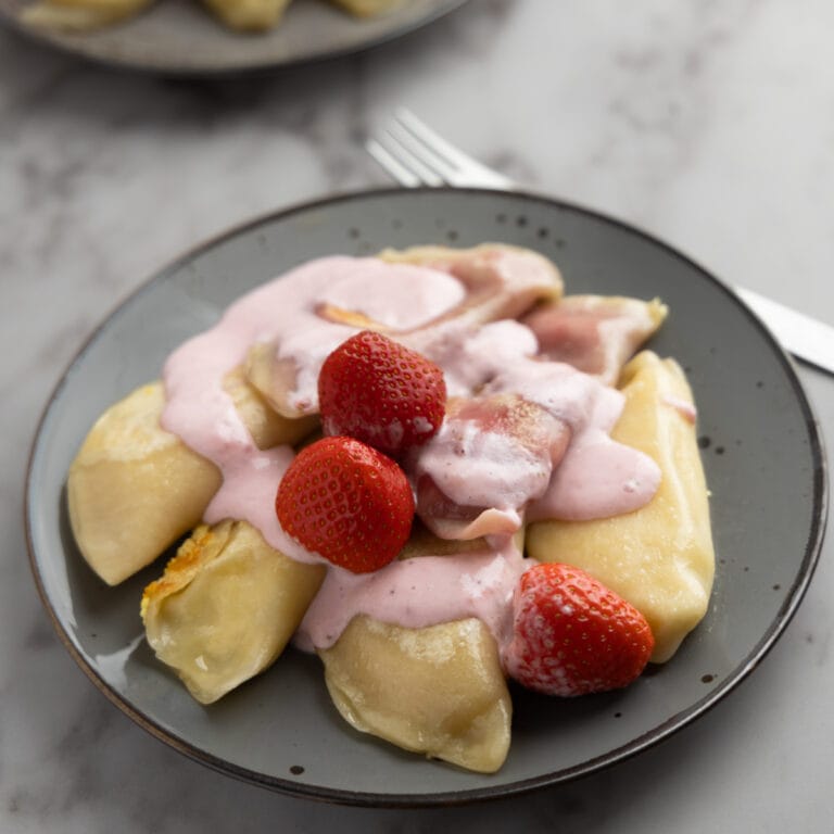 Two servings of farmers cheese pierogi strawberry topping featured