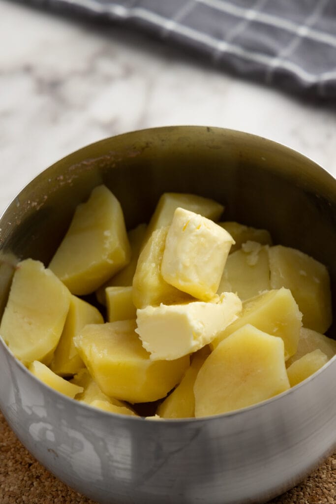 Adding butter to cooked potatoes