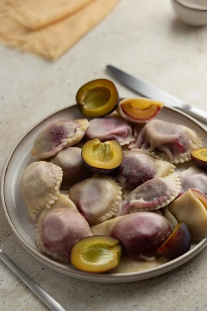 Plum pierogi served with fresh plums