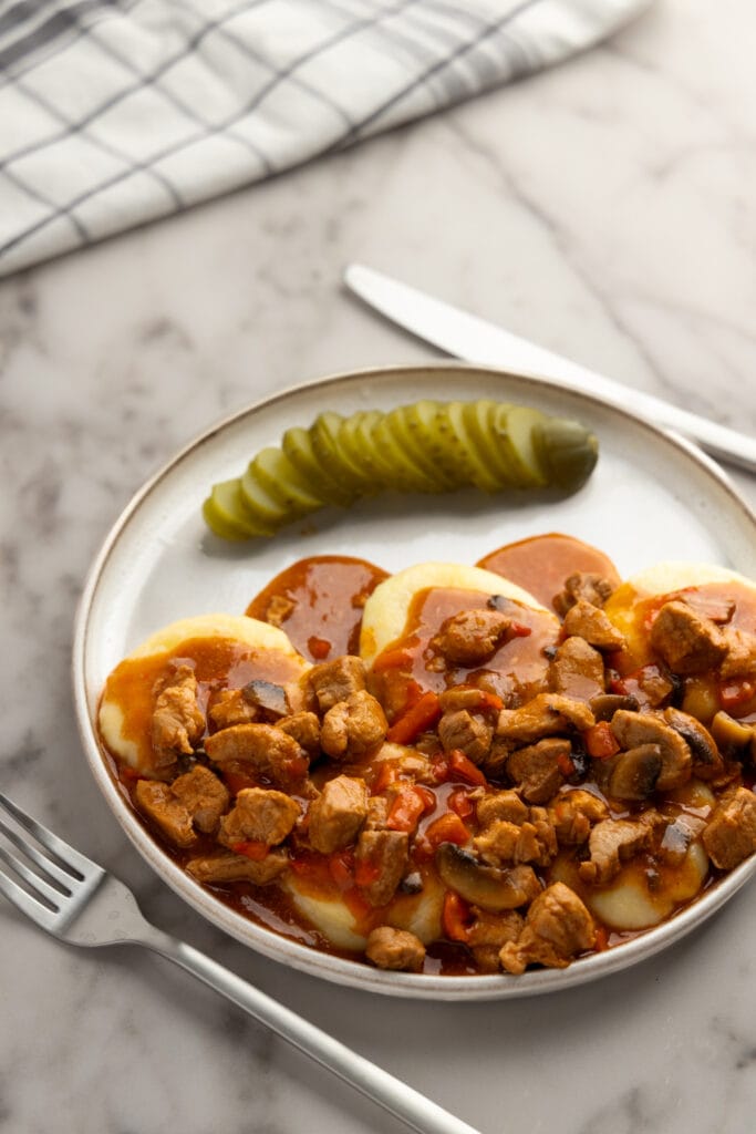 Silesian dumplings with Polish goulash and pickled cucumber
