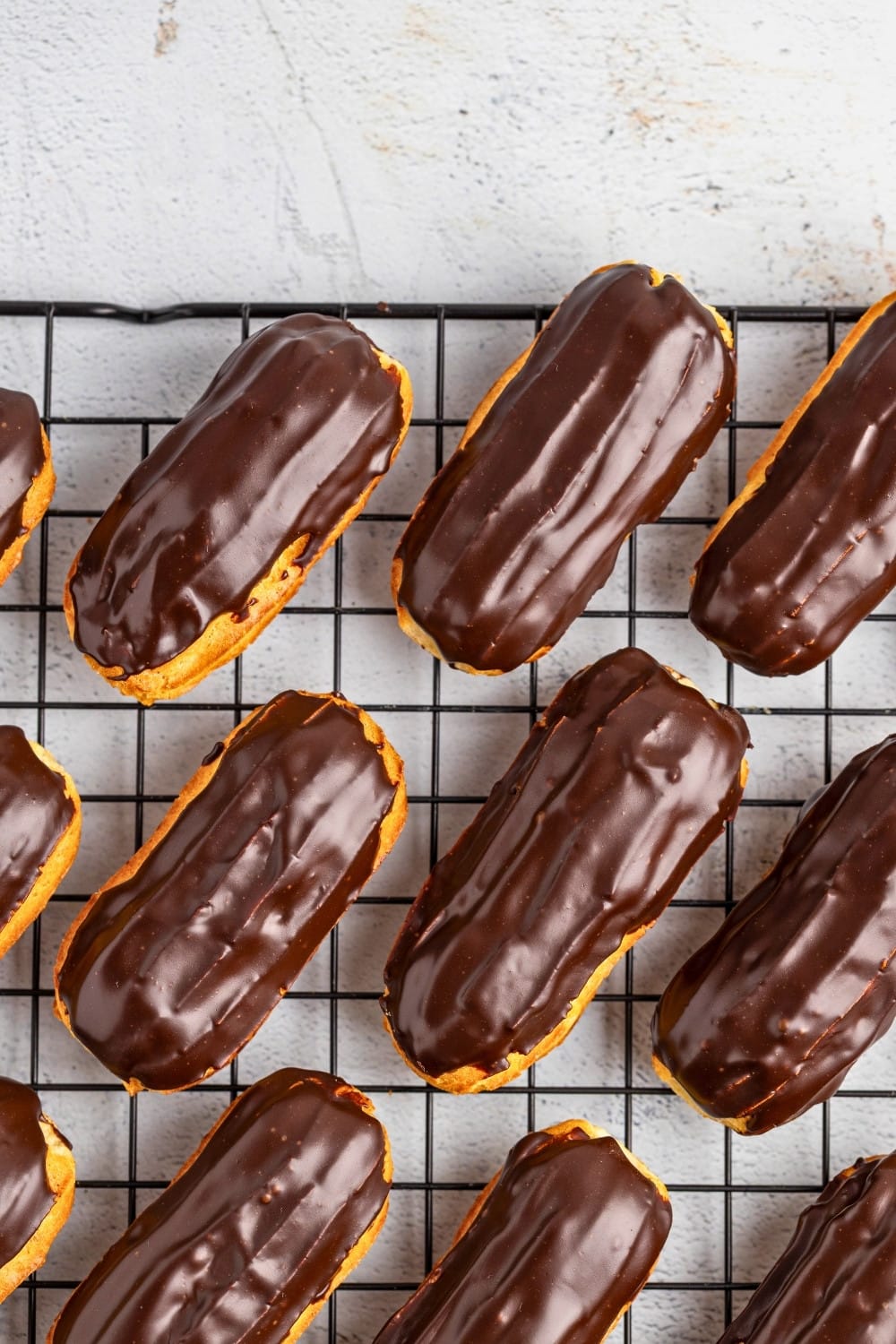Chocolate eclairs on a cooling rack topdown