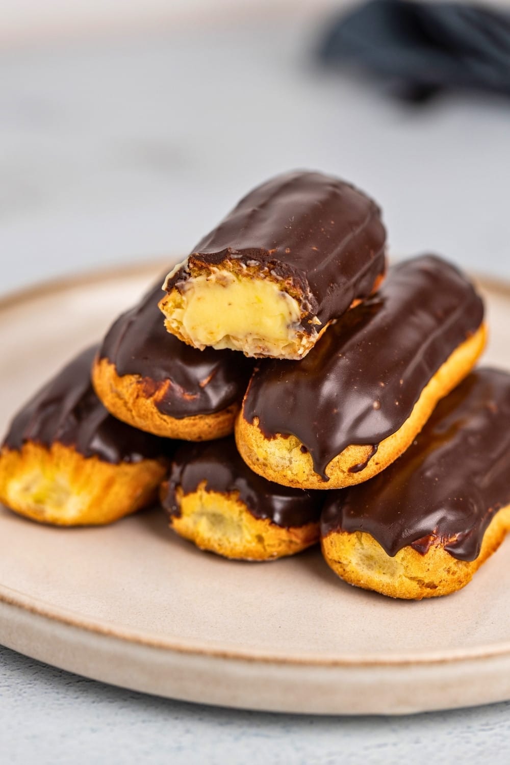 Chocolate eclairs stacked on a plate hero