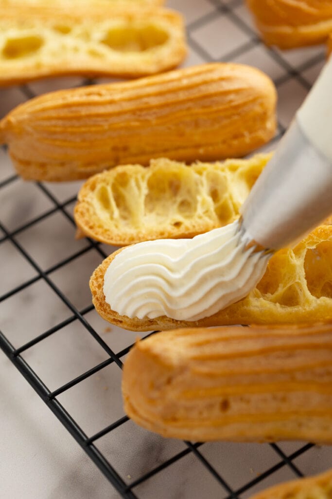 Piping whipped cream into the eclairs