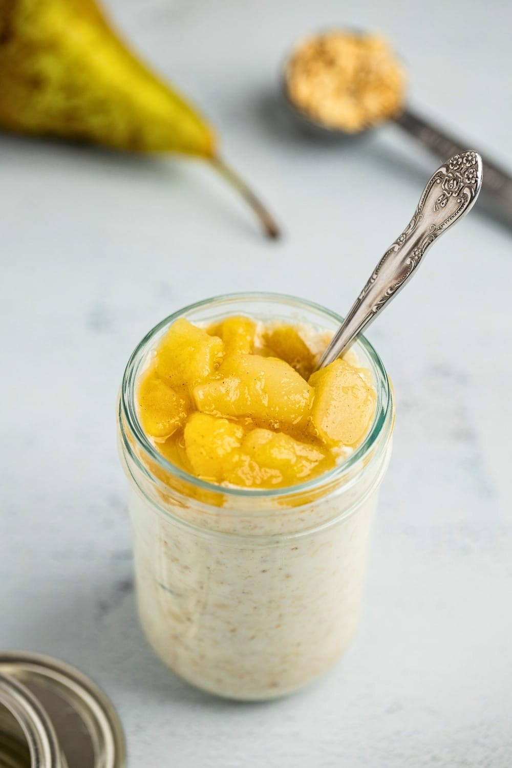 Pear overnight oats jar with a spoon