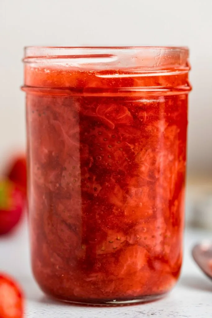 A glass jar of rich and fruity strawberry compote