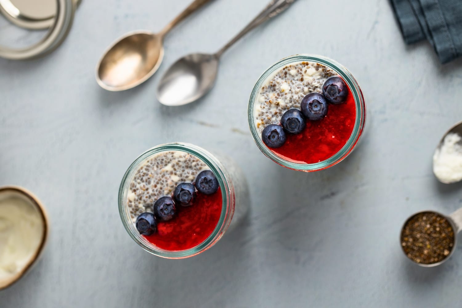 A jar of cottage cheese chia pudding with strawberry sauce and blueberries
