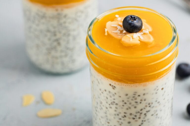 A jar of mango chia pudding with fresh blueberry nuts and shredded coconut