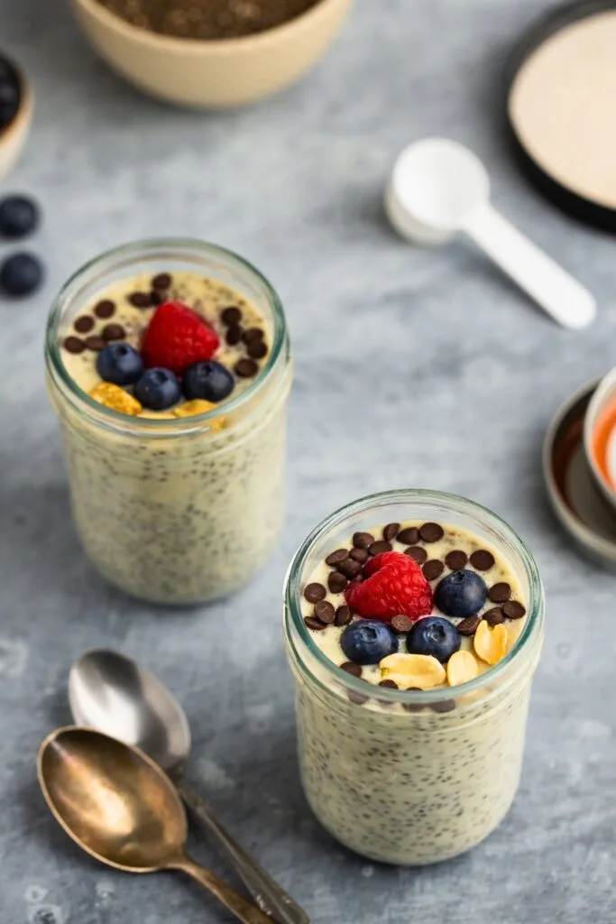 Two jars of protein powder chia pudding with raspberries and blueberries