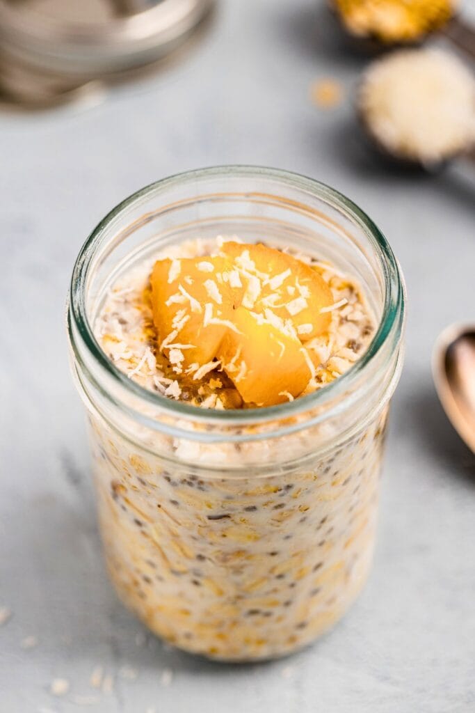 Coconut overnight oats topped with sliced peaches and shredded coconut