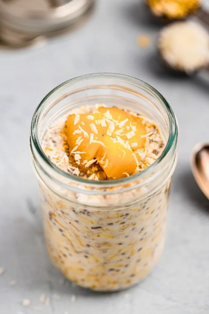 Coconut overnight oats topped with sliced peaches and shredded coconut
