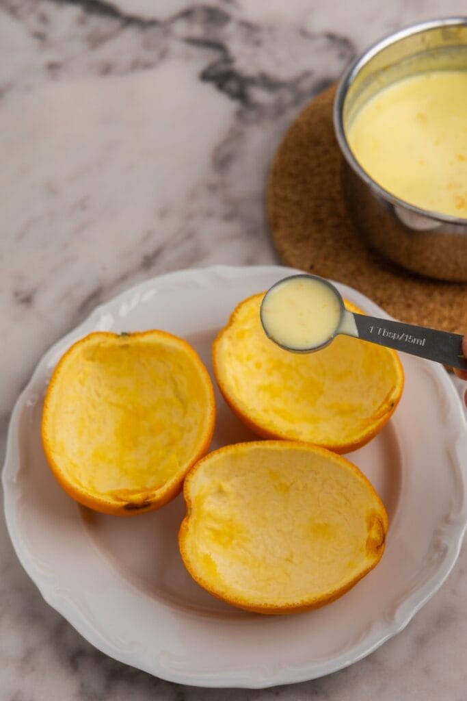 Pouring the posset into the orange shells