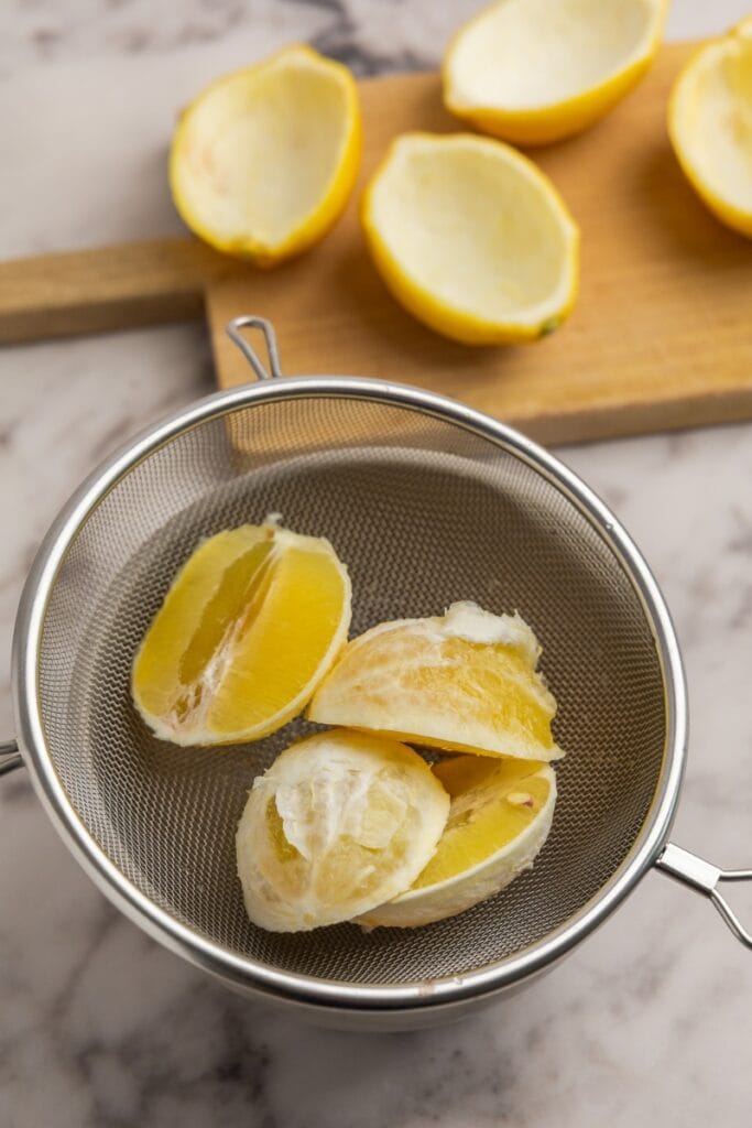 Strainer holding peeled lemon slices