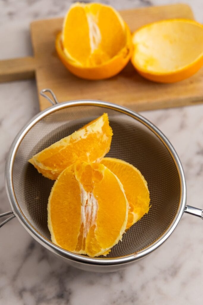 Strainer holding peeled orange slices