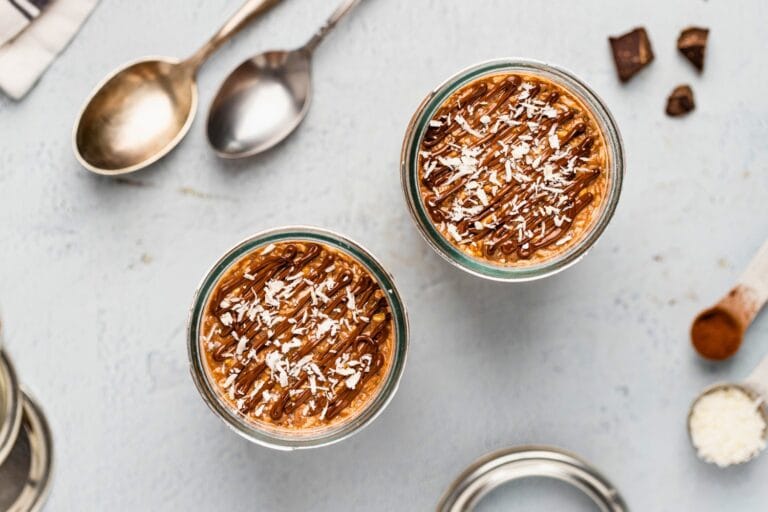 Two servings of coconut chocolate overnight oats with chocolate ganache and shredded coconut